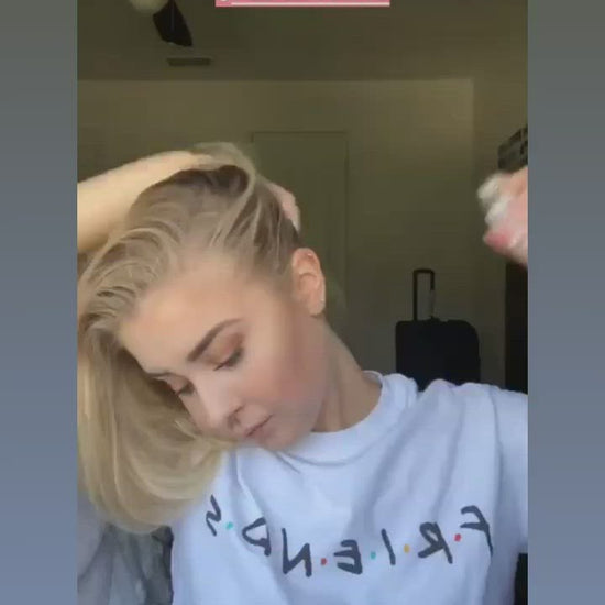 A woman in a video using a can of 12 Benefits Dry Clean dry shampoo