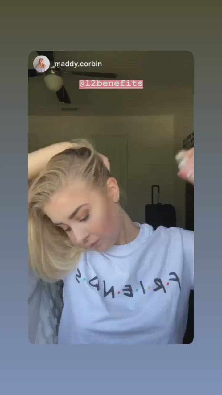 A woman in a video using a can of 12 Benefits Dry Clean dry shampoo