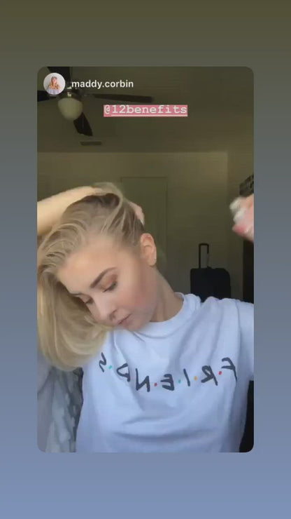 A woman in a video using a can of 12 Benefits Dry Clean dry shampoo